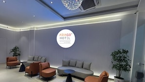 Un moderno hall de hotel con una zona de estar, un cartel grande en la pared y una lámpara en el techo.