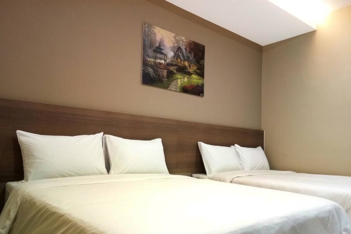 Une chambre d’hôtel avec deux lits, une tête de lit en bois et un tableau au mur.
