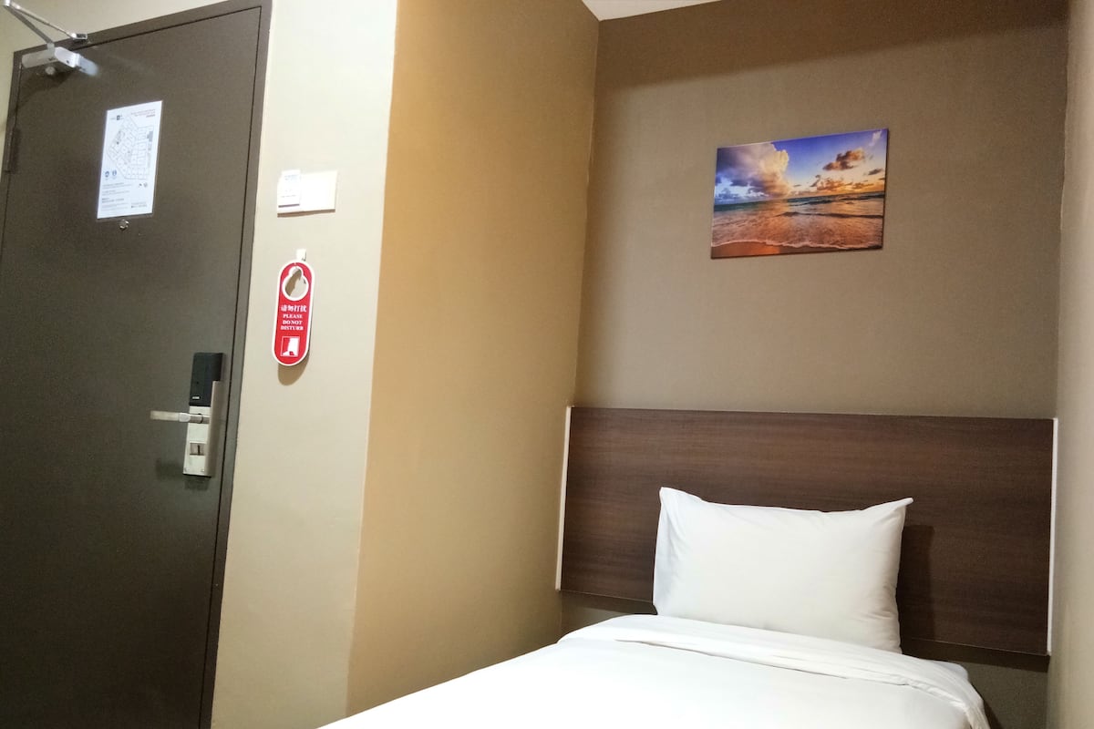 Une chambre d’hôtel avec un lit, une tête de lit, une porte et un tableau accroché au mur.