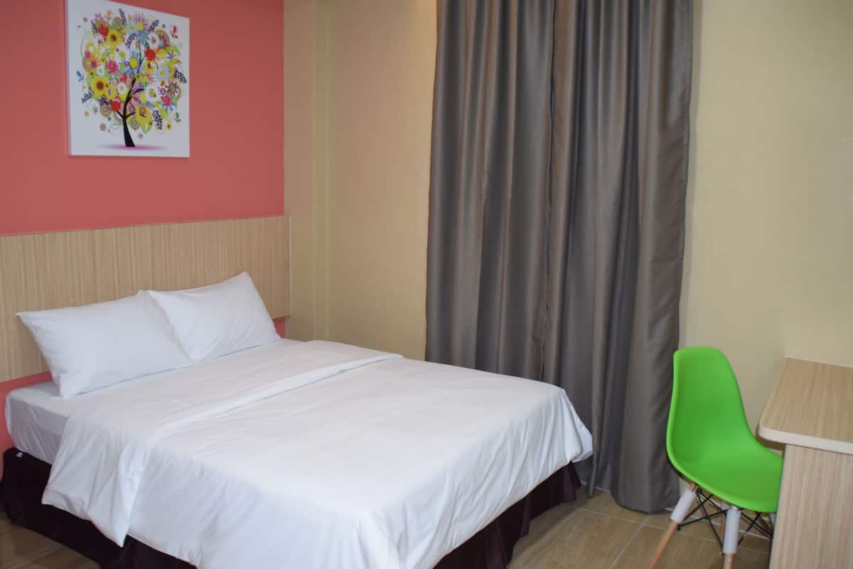 Une chambre d’hôtel avec un lit, une chaise verte, une table et un tableau au mur.