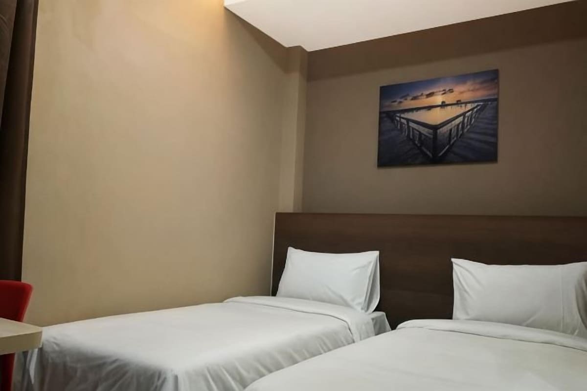 Une chambre d’hôtel avec deux lits, un tableau au mur et une vue sur le coucher de soleil.