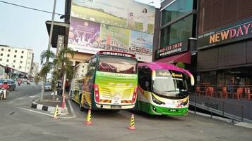 Two buses parked in front of a building with a large billboard advertising a hotel.