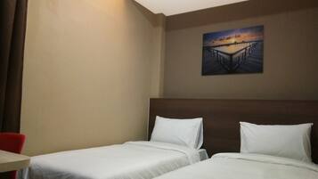 Ein Hotelzimmer mit zwei Betten, einem Schreibtisch und einem Gemälde, das einen Sonnenuntergang über einem Steg zeigt.