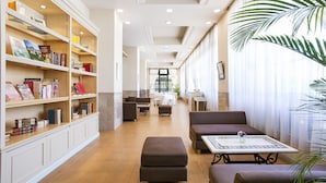 A spacious lobby with a central seating area, a bookshelf, and a dining area in the background. - Luke Plaza Hotel (Nagasaki)