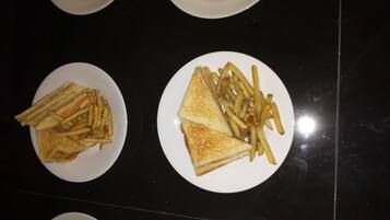 Cuatro platos blancos con sándwiches y papas fritas sobre una superficie negra.