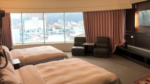 Habitación de hotel con dos camas, televisión, escritorio y vistas a la ciudad.