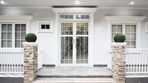 A front entrance with a double door, flanked by two windows with shutters, and two small windows above the door. - Nest Residence (Jakarta)