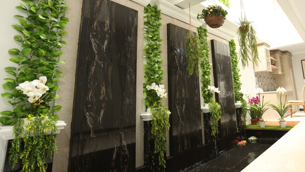 A modern interior with a black marble wall, green plants, and a water feature. - Nest Residence (Jakarta)