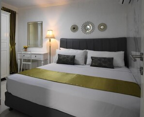 A hotel room with a bed, a desk, a lamp, and decorative wall mirrors. - Nest Residence (Jakarta)