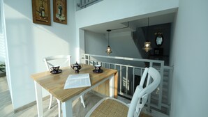 A dining area with a wooden table, white chairs, and a balcony with a railing. - Nest Residence (Jakarta)