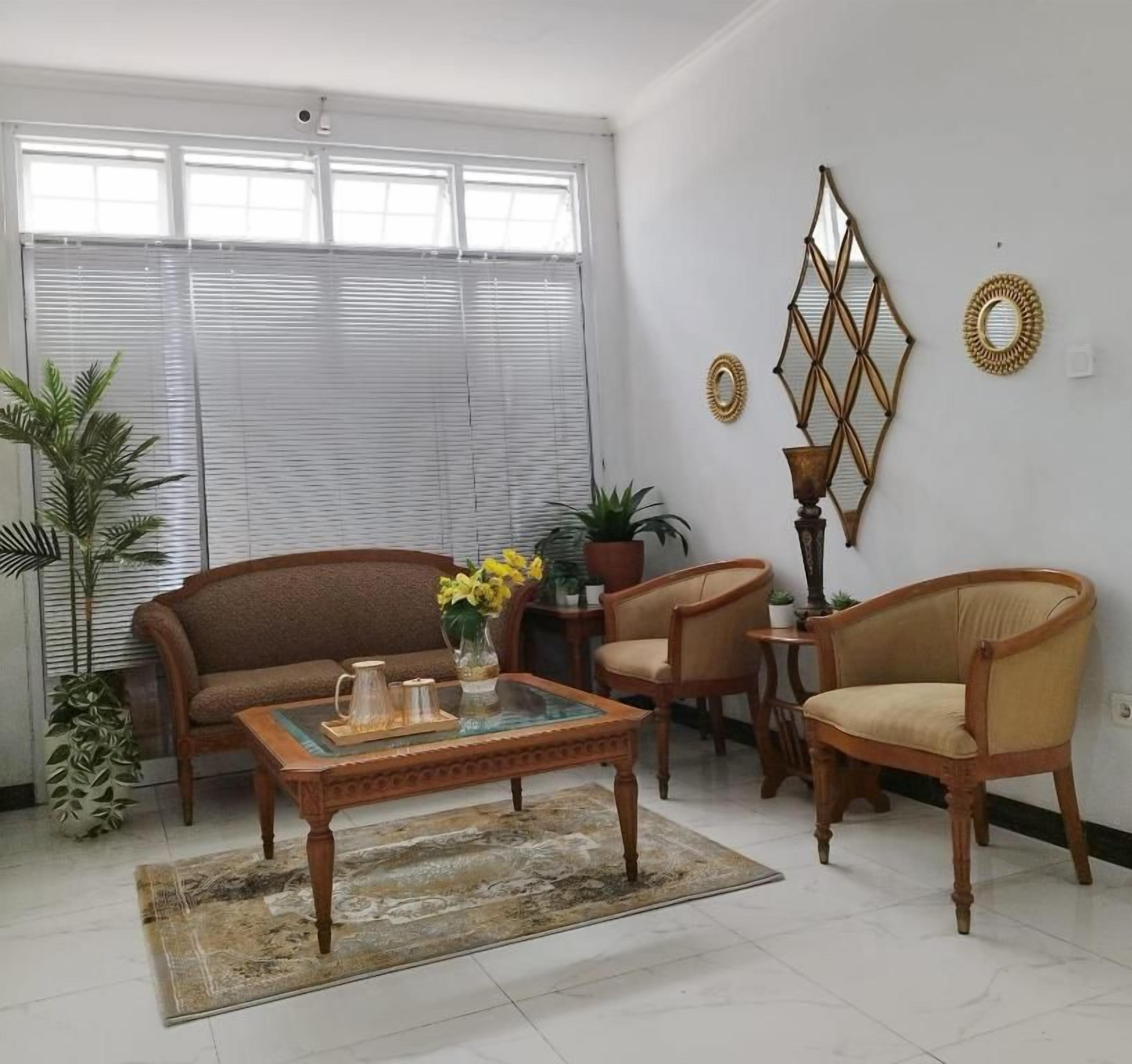 A living room with a sofa, armchairs, a coffee table, and decorative wall mirrors.
