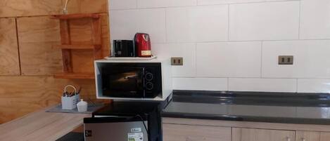 A kitchen with a microwave, a refrigerator, and a wooden cabinet.