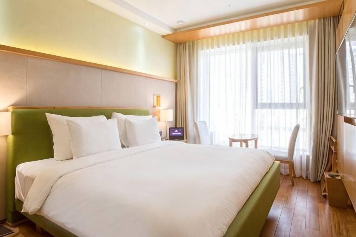 A hotel room with a large bed, a desk, a chair, and a TV.