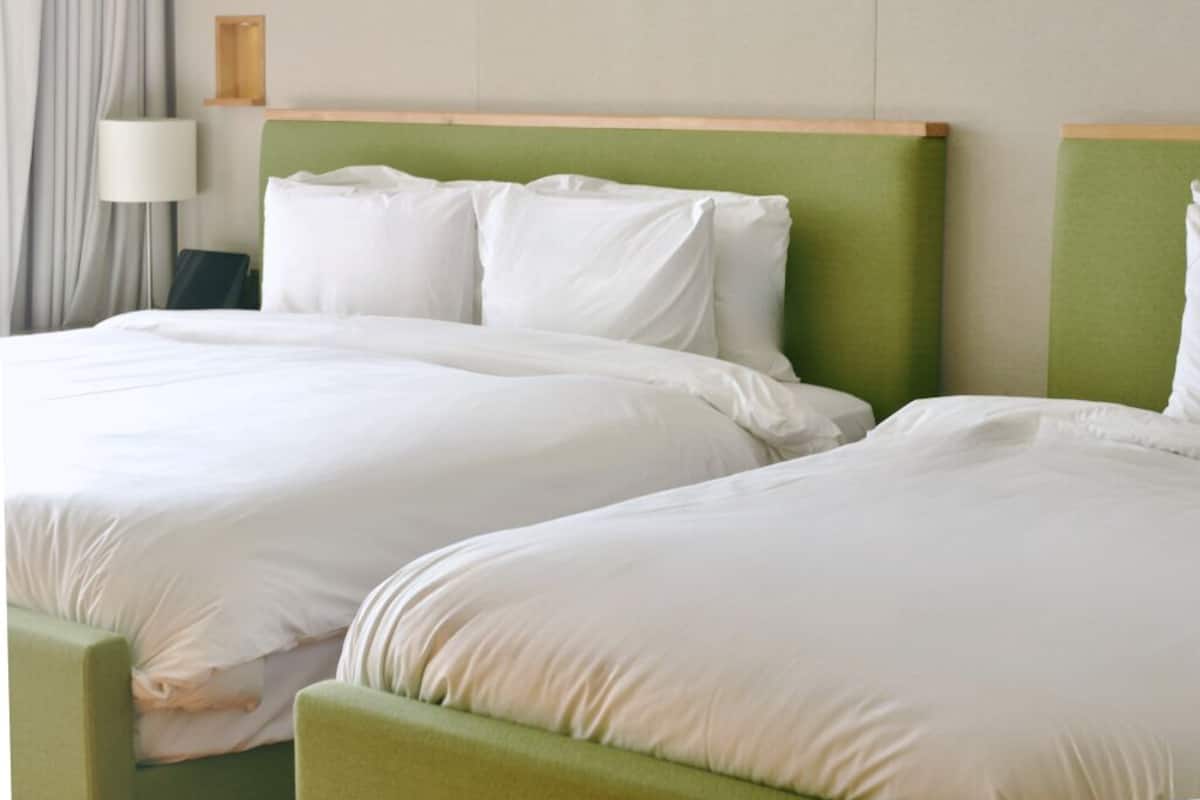 A hotel room with two beds, a lamp, and a wall-mounted shelf.