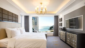 A hotel room with a large bed, a TV, and a view of the beach.