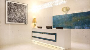 A reception desk with a modern design, a framed abstract artwork, and a decorative wall piece.