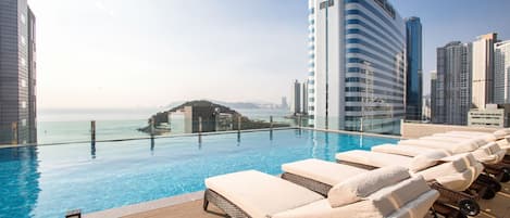 Una piscina al aire libre, camas de piscina con cargo, sombrillas
