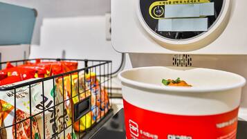 A microwave with a digital display and a red cup with food.