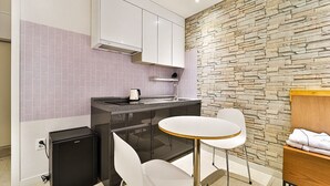 Una cocina compacta con salpicadero de pared de piedra, un refrigerador pequeño, una cafetera y una mesa redonda con dos sillas.