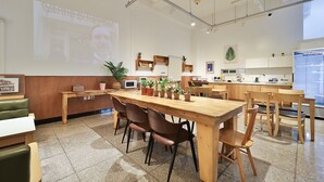 Una cocina moderna con armarios de madera, una isla grande y una pantalla de proyección mostrando a una persona.