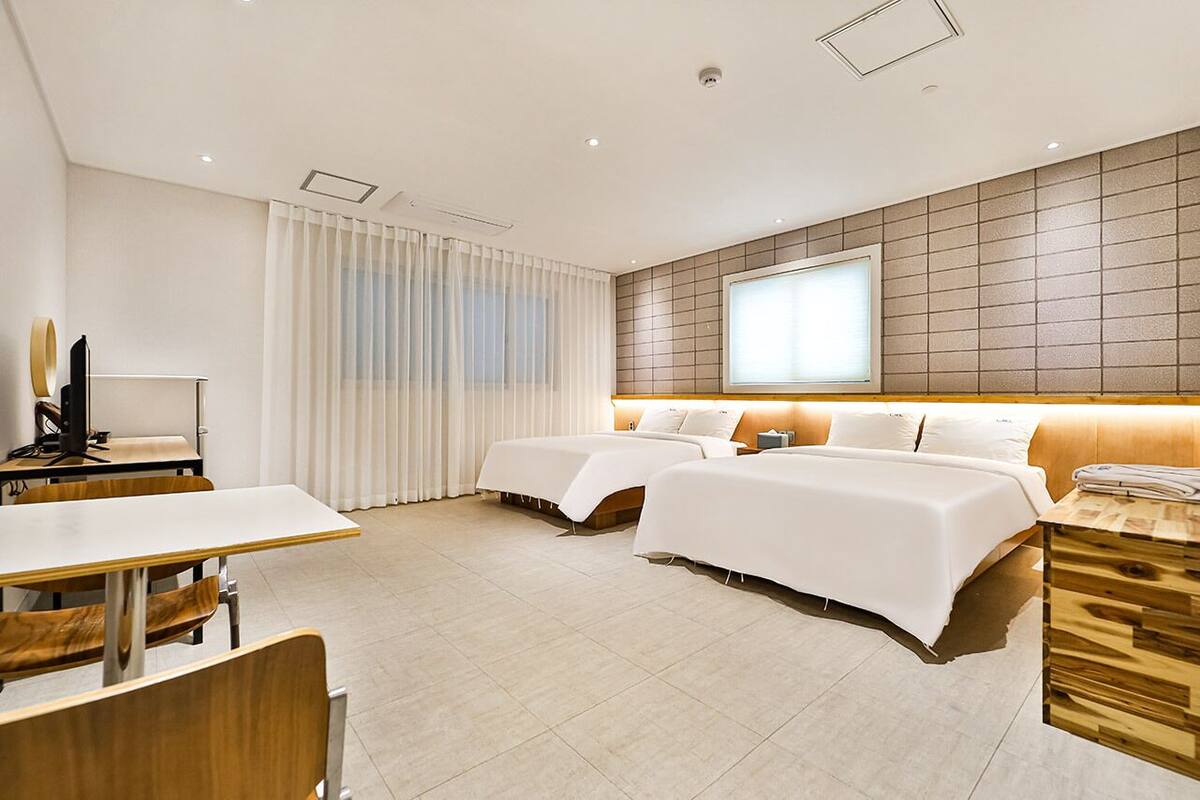 Une chambre d’hôtel moderne équipée de deux lits, d’un bureau et d’une télévision.