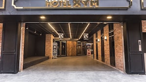 The entrance to HOTEL XYM with a modern design, featuring a brick facade, a metal sign, and a well-lit interior. - Anyang Premier Hotel XYM (Anyang)