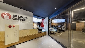 A coffee shop interior with a modern design, including a counter with a coffee machine, a fire hydrant safety panel, and digital menu boards. - Anyang Premier Hotel XYM (Anyang)