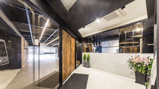A modern hotel lobby with a reception desk, a herringbone-patterned wall, and a black mat at the entrance. - Anyang Premier Hotel XYM (Anyang)