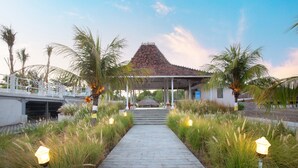 A pathway leading to a traditional-style building with a tiled roof, surrounded by palm trees and tall grasses. - FRii Resort Gili Trawangan (Gili Trawangan)