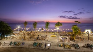 A beach with bicycles, palm trees, and string lights. - FRii Resort Gili Trawangan (Gili Trawangan)