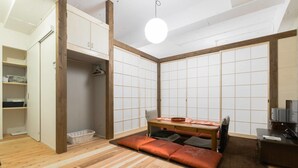 Een traditionele Japanse kamer met tatami vloeren, een lage tafel met kussens en shoji schermen.
