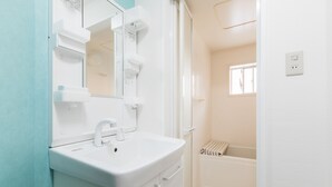 Een badkamer met een wit wastafelmeubel, spiegel en douche.