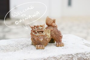 A lion statue with a speech bubble saying "Welcome to Okinawa" on a stone surface. - Onnason Resort Riora (Onna)