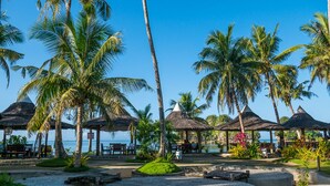 A beachside resort with palm trees, thatched-roof structures, and a clear view of the ocean. - Caluwayan Palm Island Resort (Marabut)