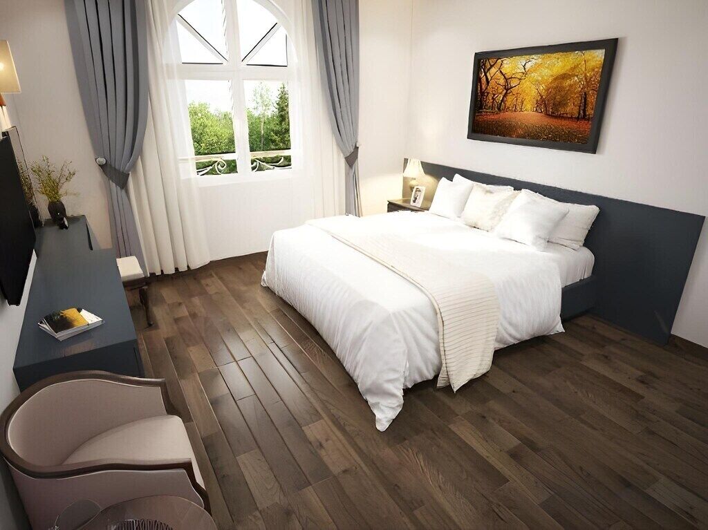 Une chambre à coucher avec un grand lit, un bureau, une chaise et une fenêtre avec des rideaux.