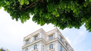 Un hotel de varios pisos con un estilo arquitectónico clásico, con balcones y una entrada destacada con escalones.