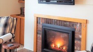A living room with a fireplace, a mounted TV, and a plaid sofa. - Ski-on/Off, Slope Views, Mountainside Top Floor, Vaulted Ceilings, Gas Fireplace (Warren)