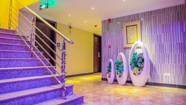 Eine Hotelhalle mit einer Marmortreppe, einem Empfangsbereich und Zierpflanzen.