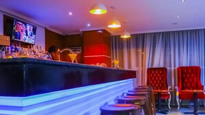 Eine Bar mit Barhocker, einer Theke und einem Fernsehbildschirm.