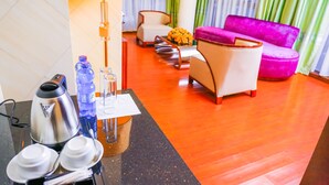 Eine Hotelhalle mit einer Kaffeestation, einem Sofa und einem Sessel.
