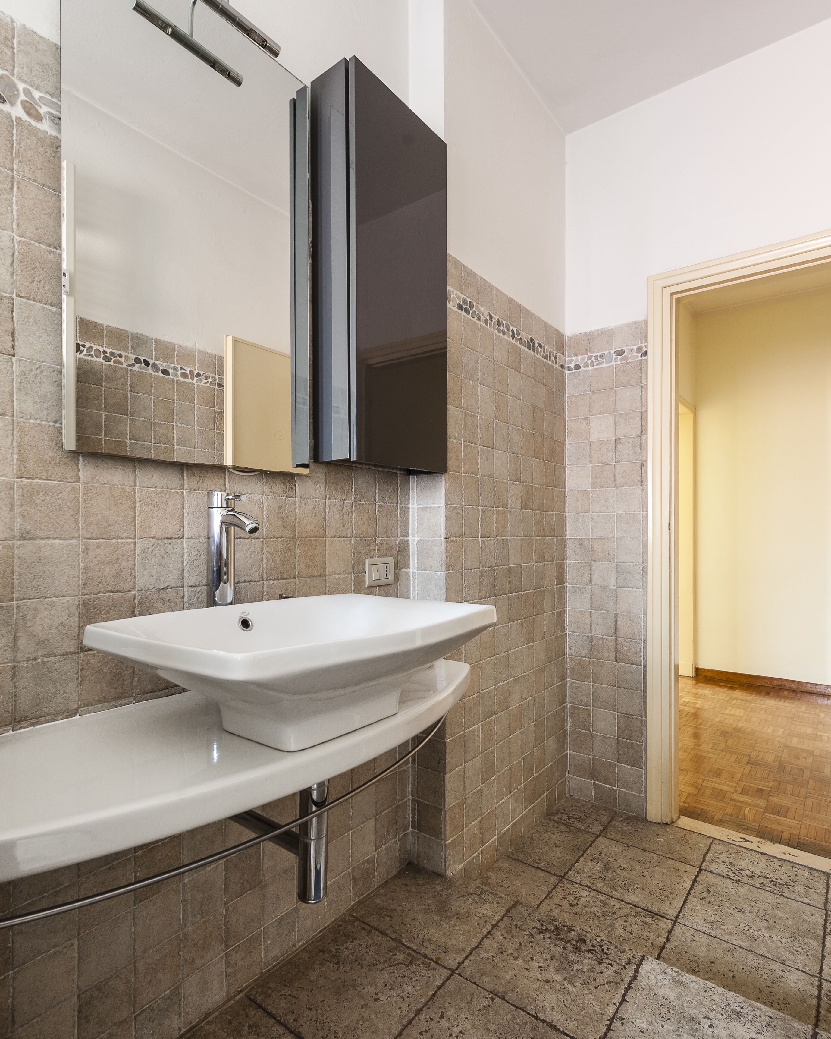 A bathroom with a white sink, a mirror, and a dark cabinet.