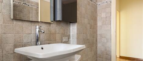 A bathroom with a white sink, a mirror, and a dark cabinet.