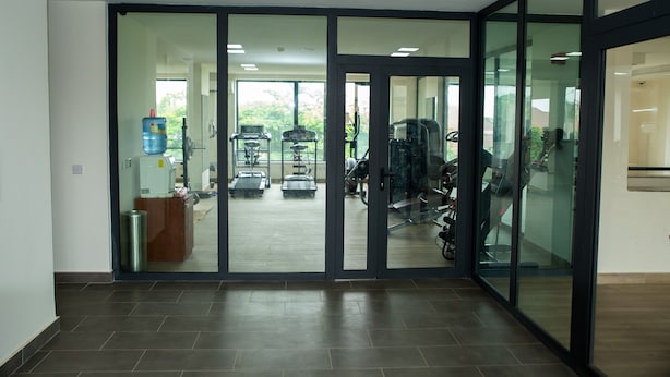 A spacious gym with exercise equipment, large windows, and a clean, modern design. - Ishakool Hotels (Abuja)