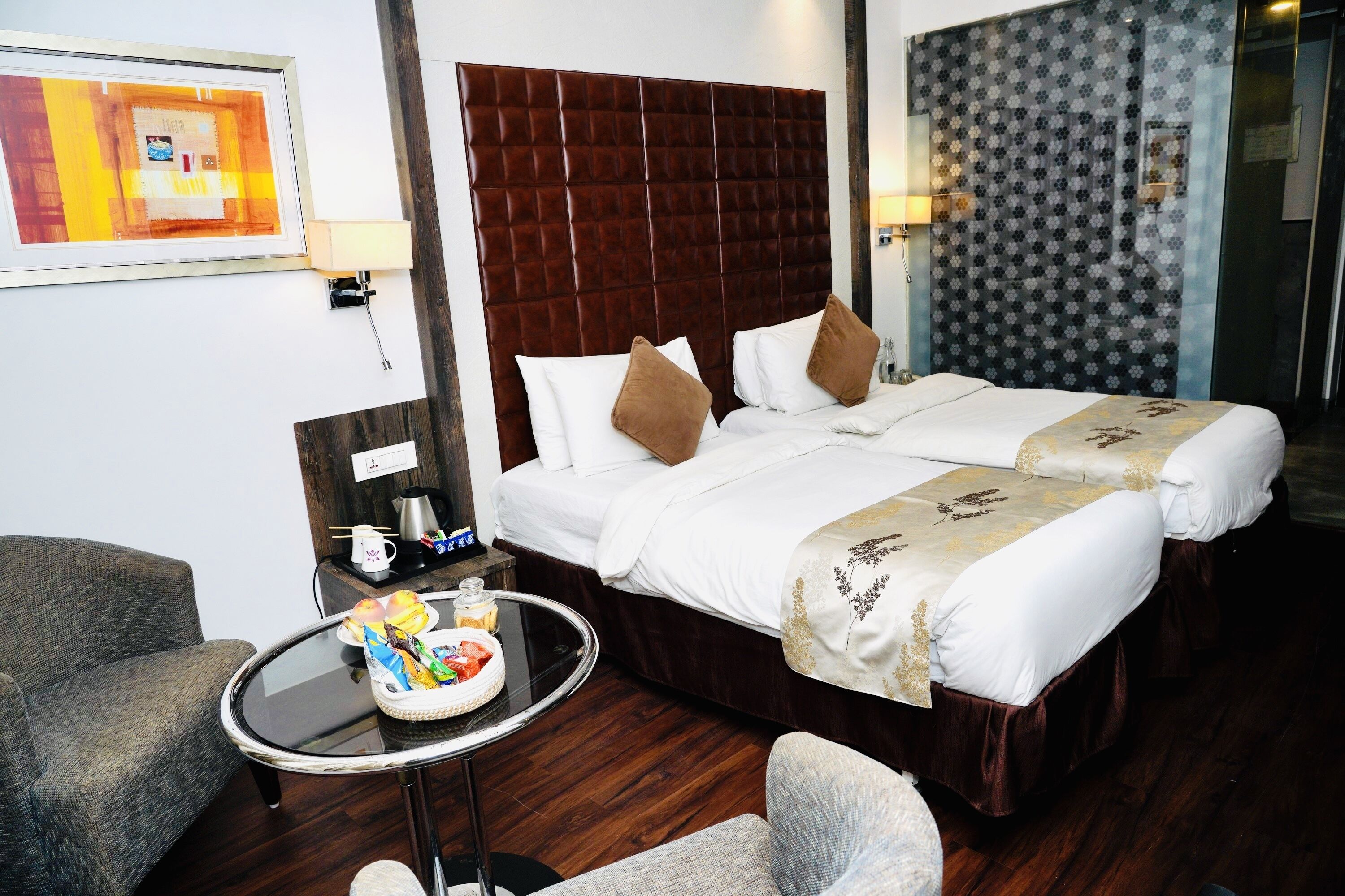 A hotel room with a large bed, a small round table, a chair, and a sofa.