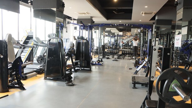 Une salle de sport équipée de divers appareils d’exercice, notamment des tapis de course, des appareils de musculation et des poids libres.