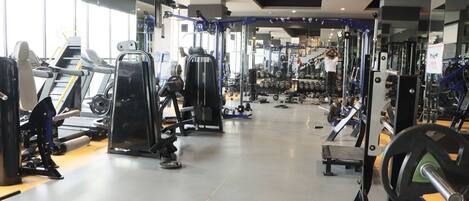 Un gimnasio con diversos equipos de ejercicio, incluyendo cintas de correr, máquinas de pesas y pesas libres.