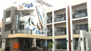 Un edificio moderno con un mural de un velero y delfines, balcones y una zona de acceso cubierta.