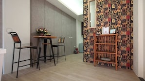A modern room with a wooden dining table and chairs, a small bookshelf, and a patterned wall. - A-Ba Homestay  (Hualien City)