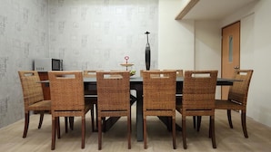 A dining area with a table and six wicker chairs, a black vase, and a microwave on the wall. - A-Ba Homestay  (Hualien City)