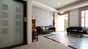 A lobby with a reception desk, a sofa, a coffee table, and a patterned floor. - A-Ba Homestay  (Hualien City)